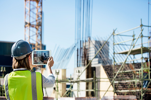 Female construction engineer taking photo of site with digital tablet