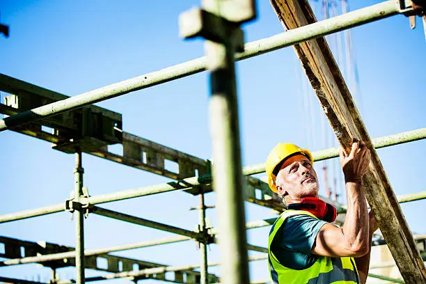 Male construction worker placing plank on structure