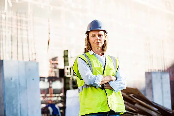 Portrait of confident female architect standing arms crossed at construction site