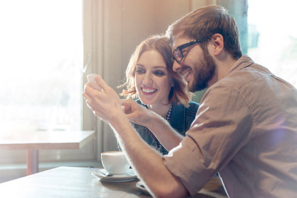 istock Couple using cell phone in sunny cafe 554391747