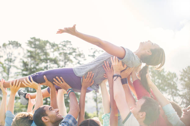 istock Carefree woman crowdsurfing supported by team 554391995