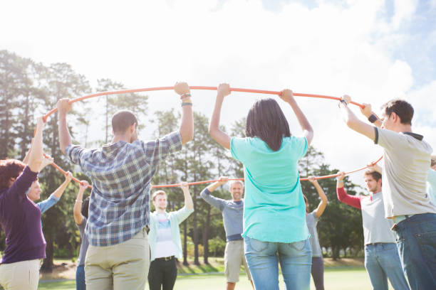 istock Team forming connected circle with plastic hoop in sunny field 554392079