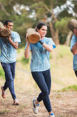 istock Woman running with log on boot camp obstacle course 554392081