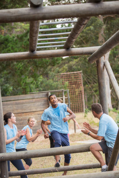 istock Teammates cheering for man nearing monkey bars on boot camp race course 554392299