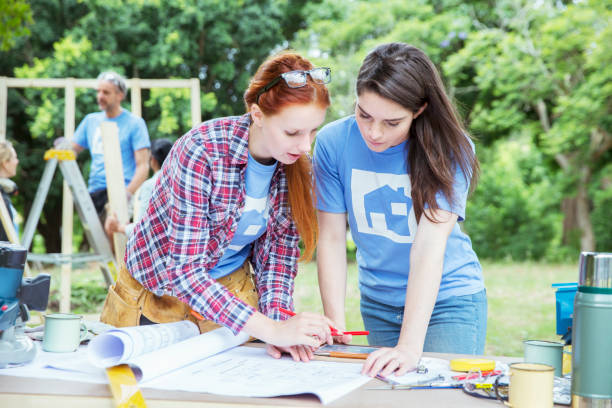 istock Volunteers with digital tablet reviewing blueprints at construction site 554392331