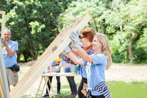 volunteers lifting construction frame at construction site - volunteer imagens e fotografias de stock