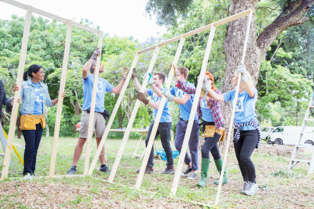 建設現場で建設フレームを持ち上げるボランティア - charity and relief work 写真 ストックフォトと画像