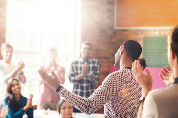 istock Audience clapping for man with arms outstretched in community center 554392391