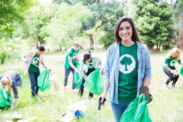 istock Portrait of smiling environmentalist volunteer picking up trash 554392439