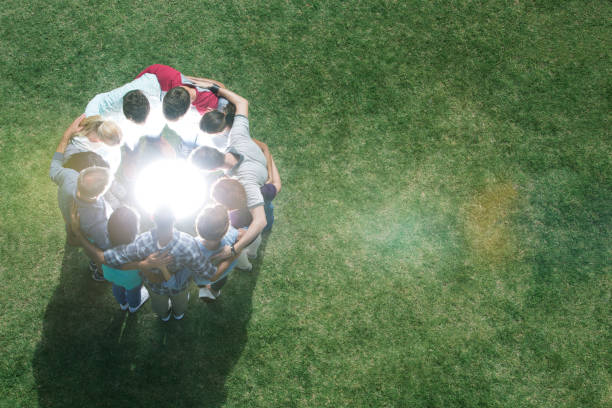 istock Team huddled in circle around glowing orb in field 554392465