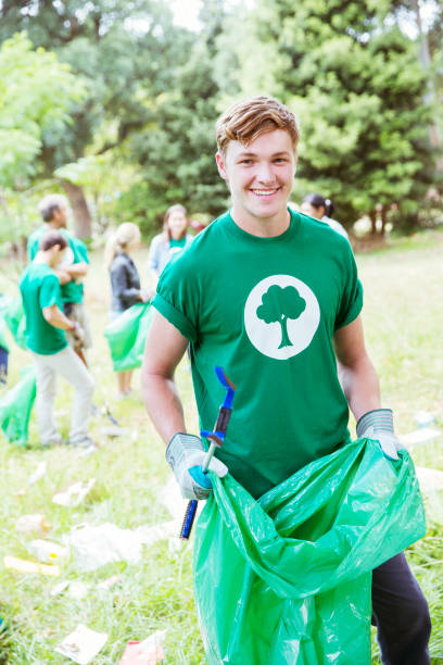 istock Portrait of smiling environmentalist volunteer picking up trash 554392493