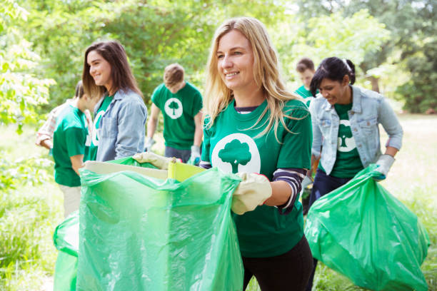 smiling environmentalist volunteer picking up trash - bag garbage bag plastic black imagens e fotografias de stock