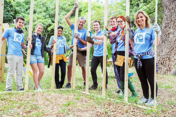 istock Portrait of smiling volunteers holding construction frame at construction site 554392713
