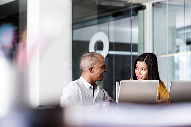 Business people discussing in office Multi-ethnic business people discussing at desk in office differential focus stock pictures, royalty-free photos & images