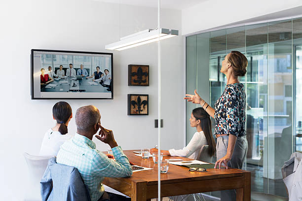 Business people video conferencing in board room Multi-ethnic business people video conferencing at desk in board room conference call stock pictures, royalty-free photos & images