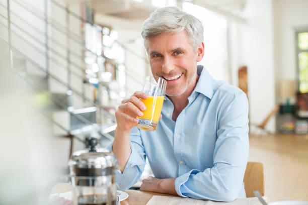 istock Older man drinking orange juice at breakfast table 555798925
