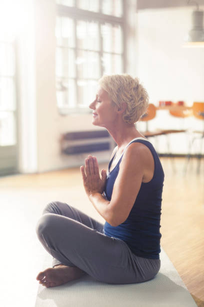 istock Older woman meditating on exercise mat 555798953