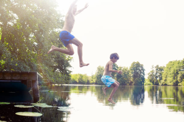 istock Father and son jumping into lake 555799457