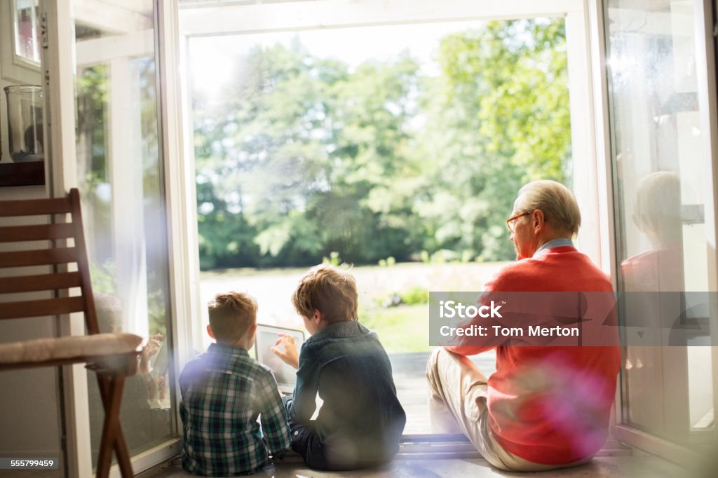 Grandfather and grandsons relaxing in doorway  Senior Adult Stock Photo