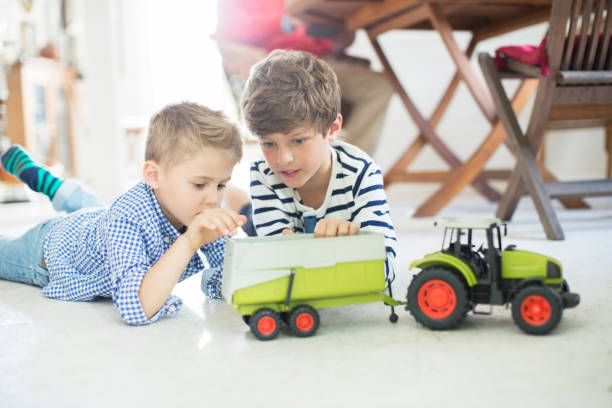 Young boy carefully plays and creates a scenario based on the roadwork taking place outside of his home. Imaginary play is difficult for children like him on the spectrum, but having the real truck on the street in front of his home helped him make a connection.