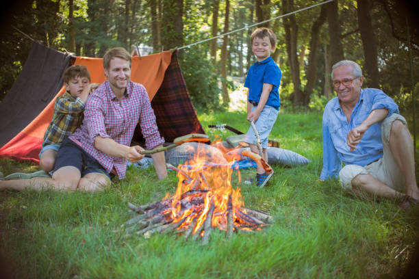 istock Boy, father and grandfather relaxing near campfire 555799503