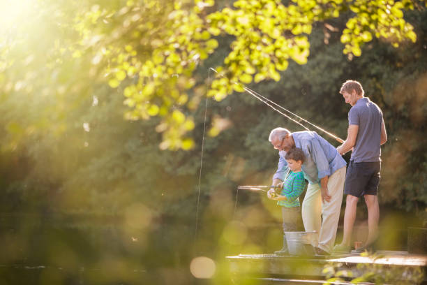 niño, padre y abuelo pescando en el lago - grandchild grandparent child senior adult fotografías e imágenes de stock