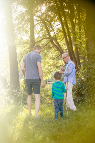 istock Boy, father and grandfather walking in forest 555799523