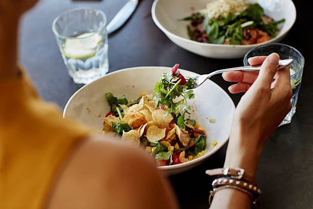 Woman having food at restaurant table Cropped image of woman having food at restaurant table food table stock pictures, royalty-free photos & images