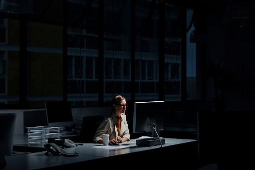 Empresaria usando la computadora en la oficina oscura photo