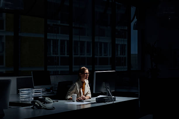 imprenditrice che usa il computer in ufficio buio - scuro immagine foto e immagini stock
