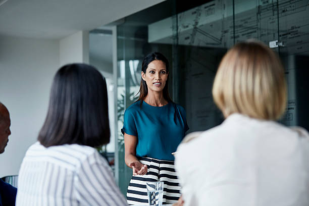 imprenditrice che discute con il team in sala riunioni - women businesswoman elegance skirt foto e immagini stock