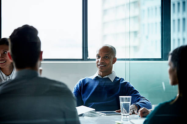 istock Businessman with colleagues at conference table 557608491