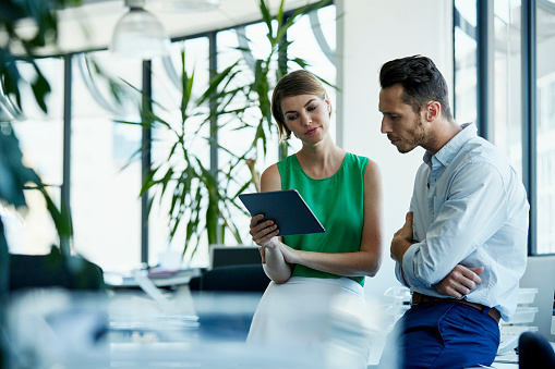 Young businessman and businesswoman using digital tablet in office