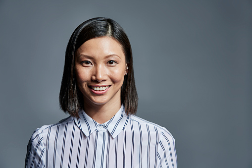 Portrait of smiling young businesswoman over gray background