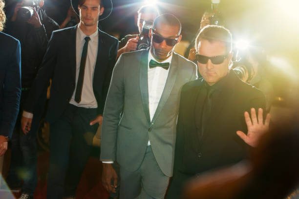 bodyguard escorting celebrity arriving at event - smoking issues fotos imagens e fotografias de stock