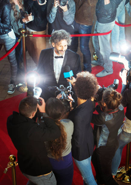 istock Celebrity being interviewed and photographed by paparazzi at event 559536487