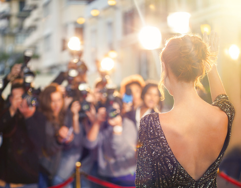 Celebrity waving at paparazzi photographers at event