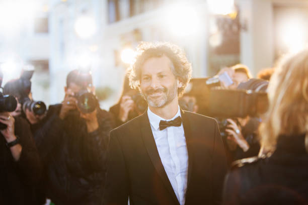 Smiling celebrity being photographed by paparazzi at event  tuxedo photos stock pictures, royalty-free photos & images