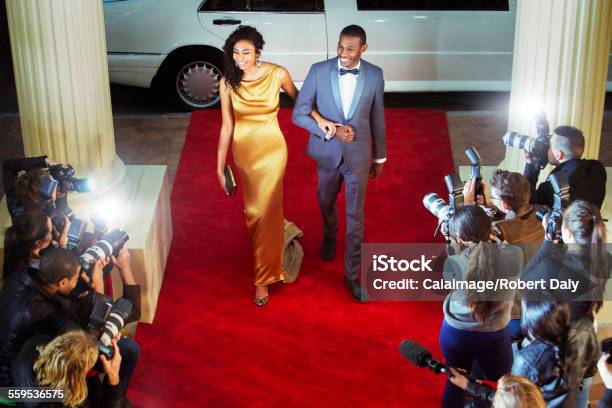 Celebrity Couple Arriving At Red Carpet Event And Being Photographed By Paparazzi Stock Photo - Download Image Now