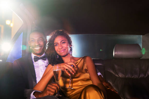 istock Smiling celebrity couple drinking champagne inside limousine outside event 559536577