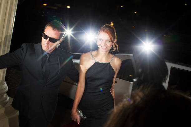 bodyguard begleitet lächelnde berühmtheit bei der ankunft bei der veranstaltung - business suit sunglasses diagonal stock-fotos und bilder