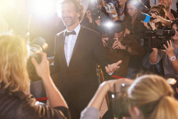 istock Smiling celebrity posing for paparazzi photographers at event 559536743