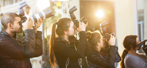 istock Paparazzi photographers in a row pointing cameras at event 559536833