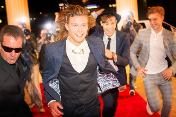 Enthusiastic celebrities arriving and running from paparazzi at red carpet event  boy band stock pictures, royalty-free photos & images