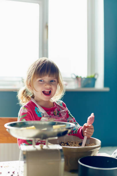 istock Smiling girl baking with mixing bowl in kitchen 559537525