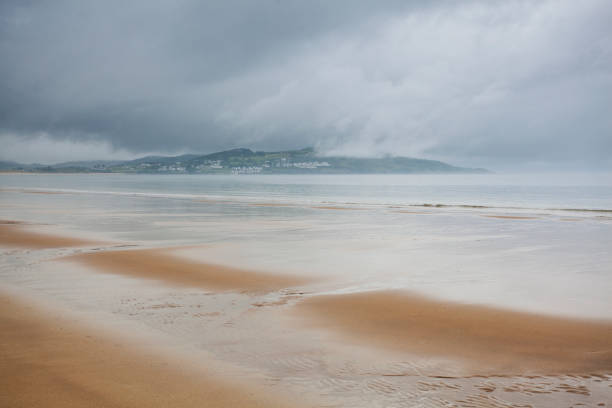 Blue skies with rolling rainclouds over a flat and calm sea
