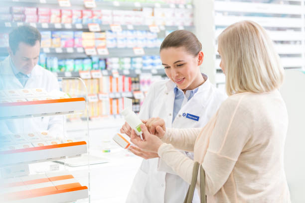 pharmacist and customer reviewing label on box in pharmacy - women customer service representative service standing imagens e fotografias de stock