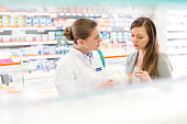 Pharmacist and customer discussing prescription in pharmacy