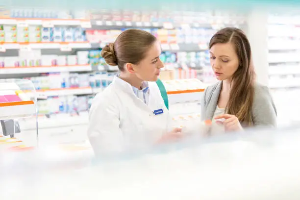 Photo of Pharmacist and customer discussing prescription in pharmacy