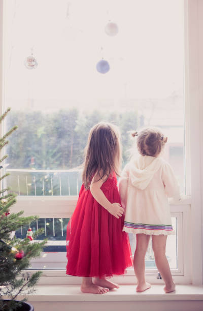 istock Girls on window ledge below Christmas ornaments 559538499